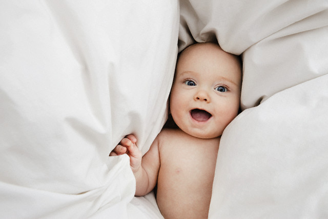 Baby laying on blanket --- Image by © Bernd Vogel/Corbis