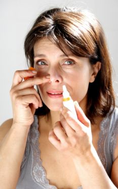 Woman using nasal spray. Model released. A nasal spray packed with viruses could ease the devastating symptoms of Alzheimer's disease. MIDDLE AGE AGED 675286ak
